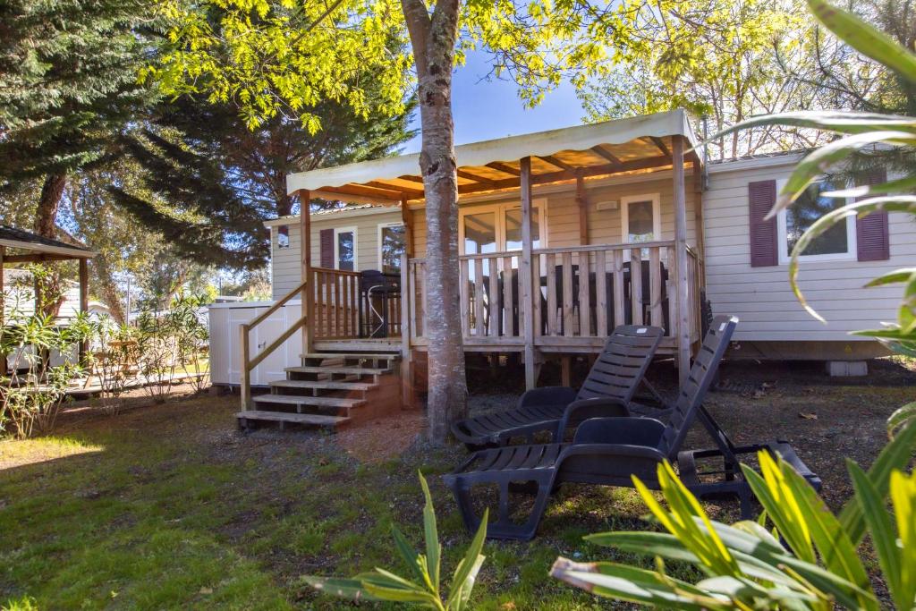 a tiny house with a porch and two chairs at Mobilhome Camping Siblu les Viviers in Lège-Cap-Ferret