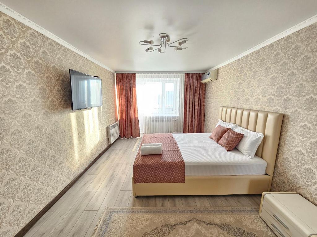 a bedroom with a bed and a tv on a wall at Mars APARTMENTS KZ 1 in Aktobe