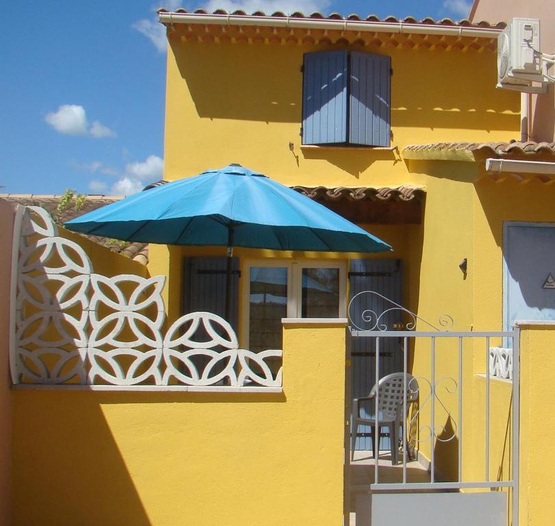 un bâtiment jaune avec un parapluie bleu sur un balcon dans l'établissement vacances en provence cyprès, à Mormoiron