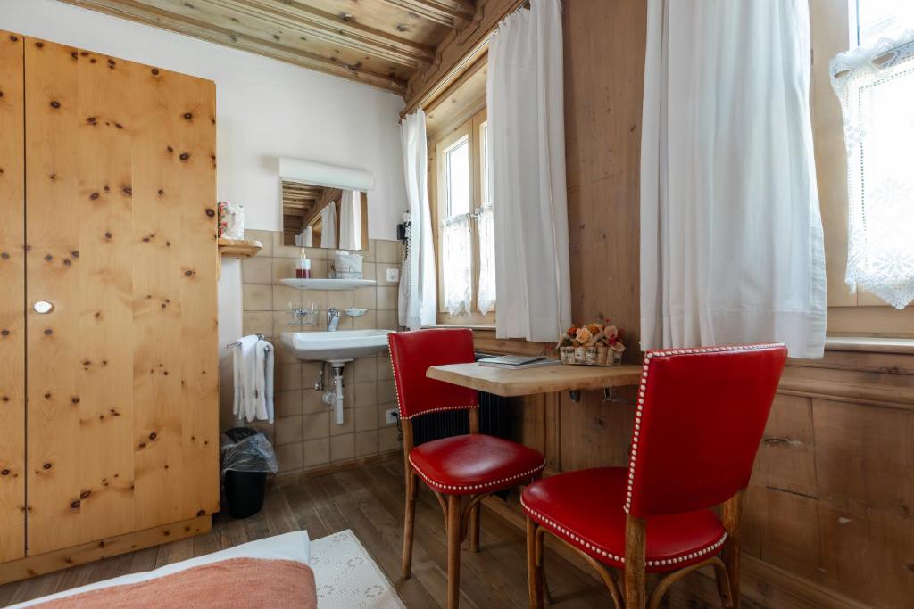 a bathroom with red chairs and a table and a sink at Palazzo Mysanus Samedan in Samedan