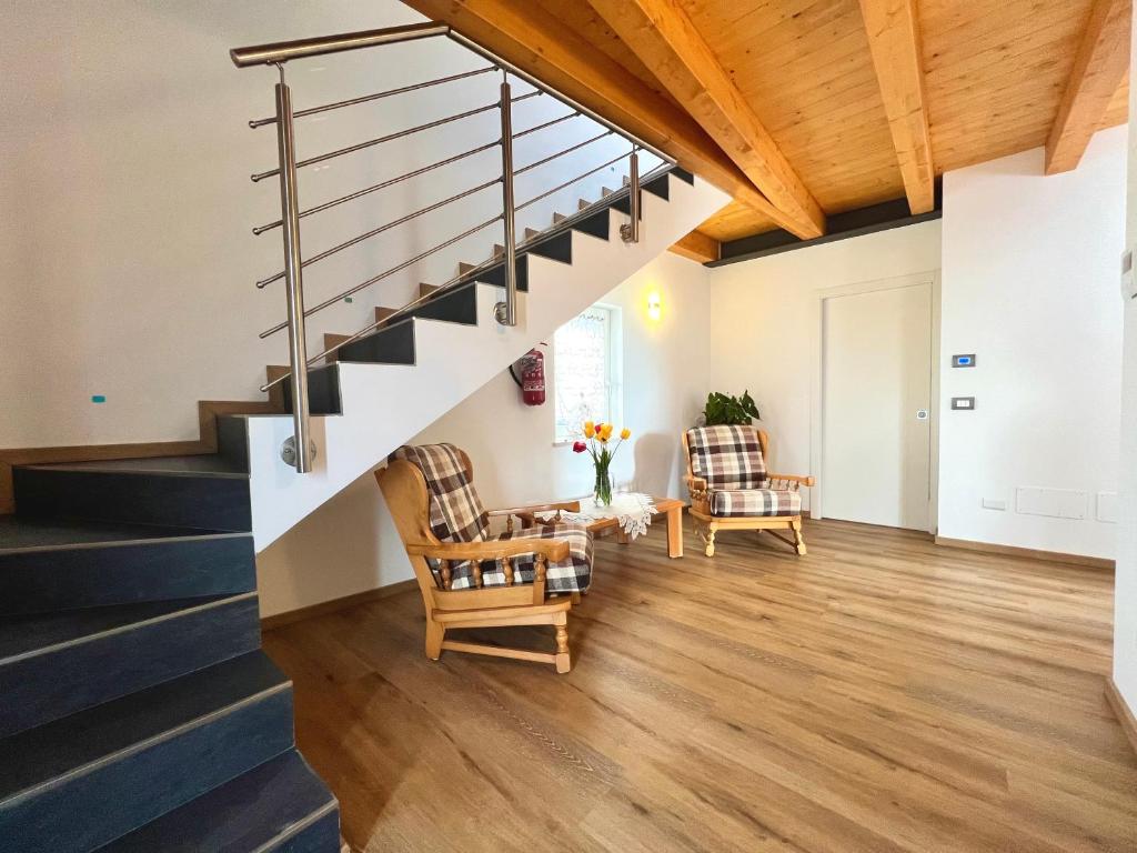 a living room with stairs and two chairs at Sogno Blu - Levico in Levico Terme