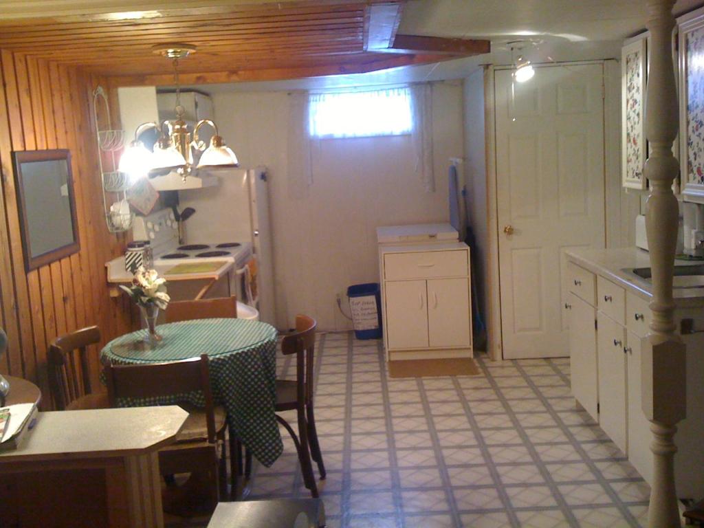 a small kitchen with a table and a kitchen with a refrigerator at Mining Rooms Gaspé Murdochville in Gaspé