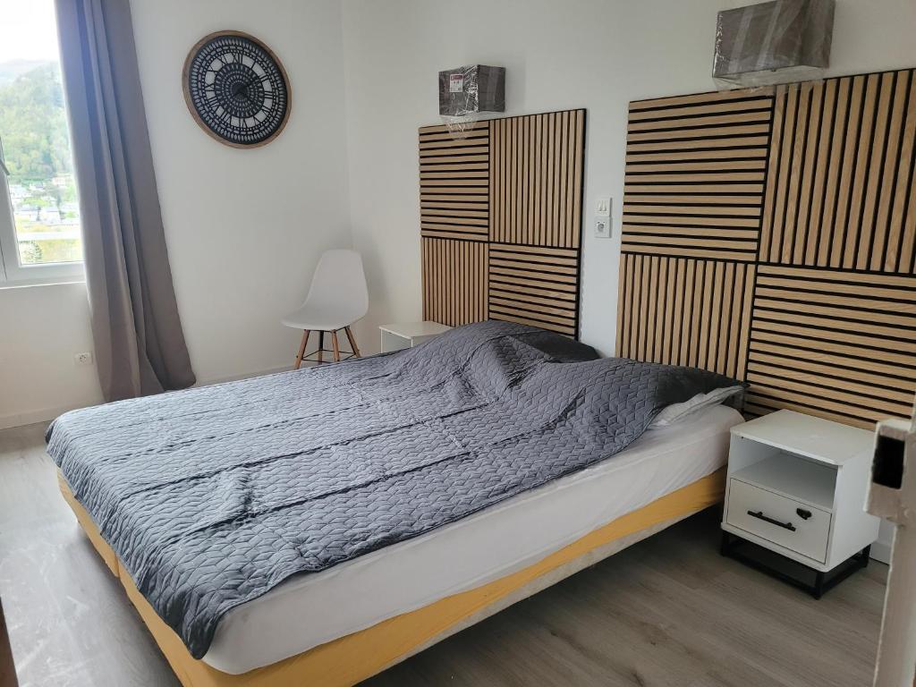 une chambre avec un lit et une horloge au mur dans l'établissement Le randonneur, à Vic-sur-Cère