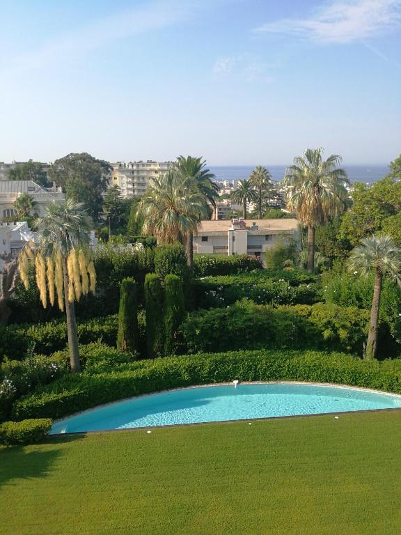 une piscine dans un parc avec des palmiers dans l'établissement CANNES Vue Mer & Balcon dans Villa Exceptionnelle Belle Époque la Californie, à Cannes