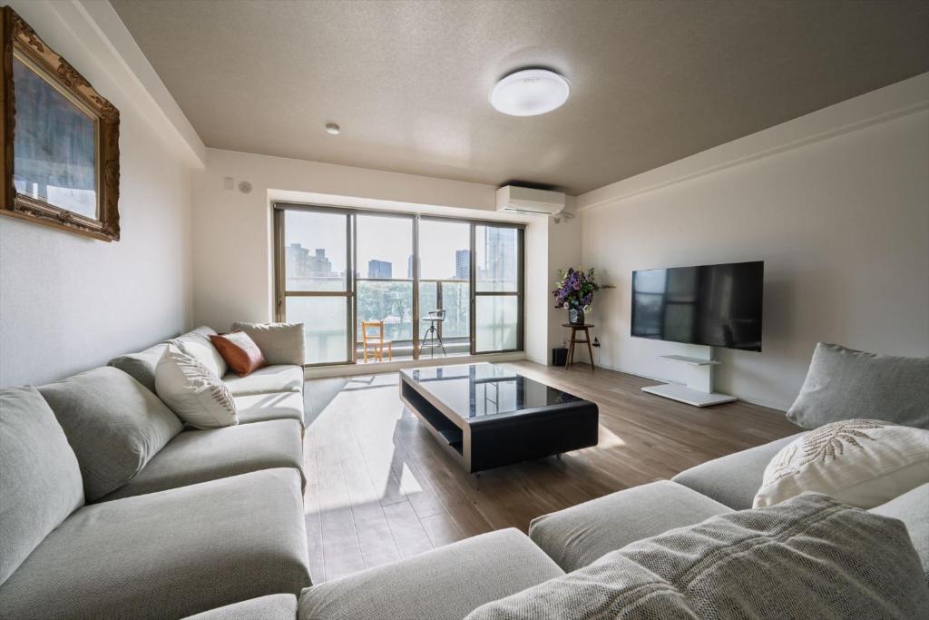 a living room with a couch and a tv at LIT広島駅前 広島駅から徒歩5分 全室リバービューでベッドはairweaveを採用 Spacious rooms with river views all to yourself Supported in Ōsukachō