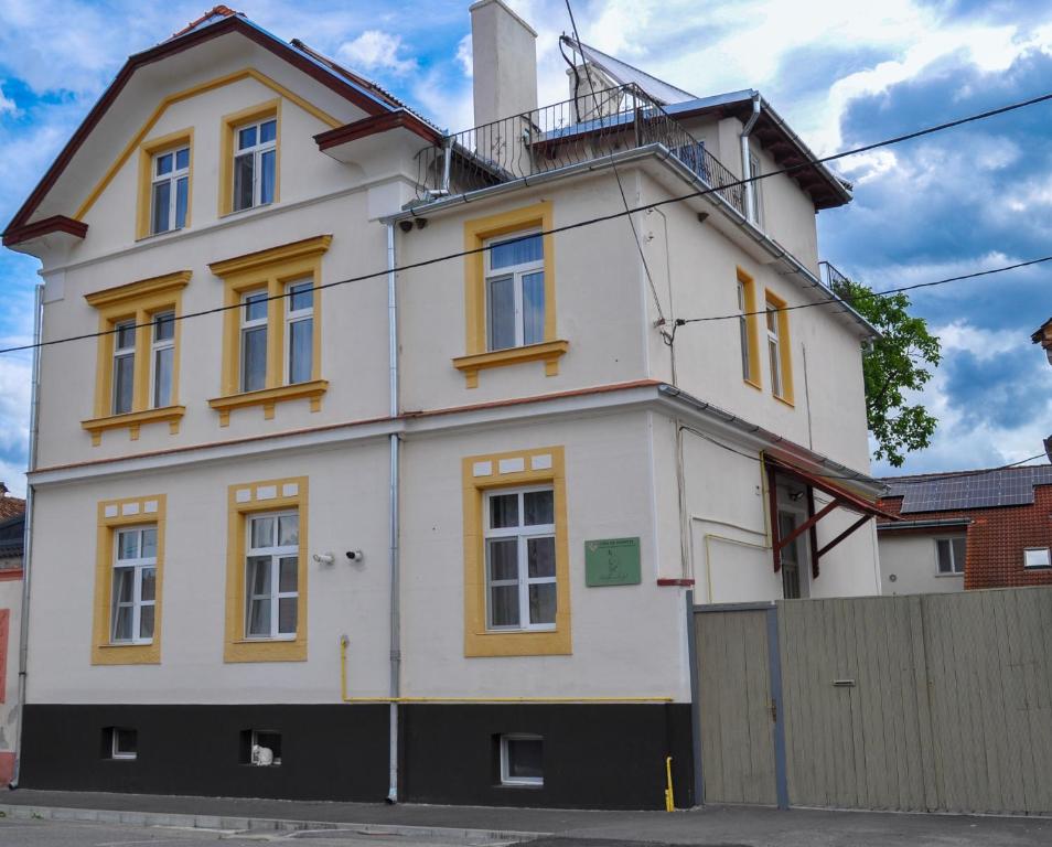 a white house with yellow windows and a fence at Casa de Oaspeți Vulcan in Braşov