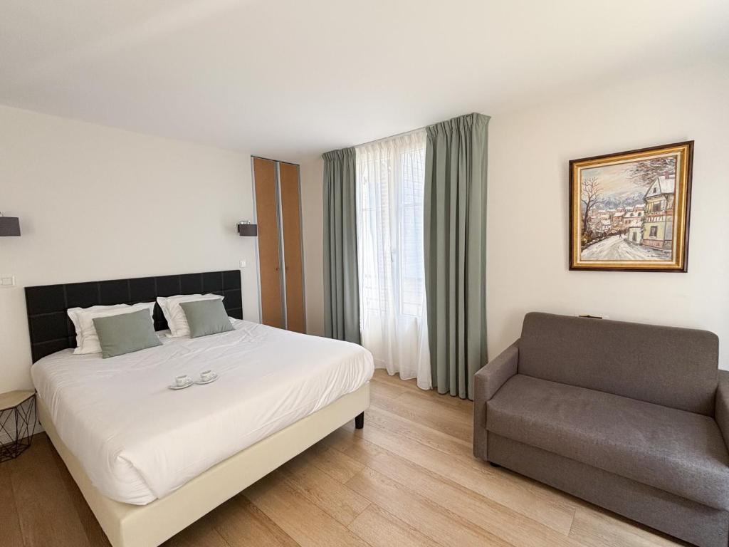 a hotel room with a bed and a couch at Les Maisons d'Eugène Appart'Hôtel - Centre Historique in Honfleur