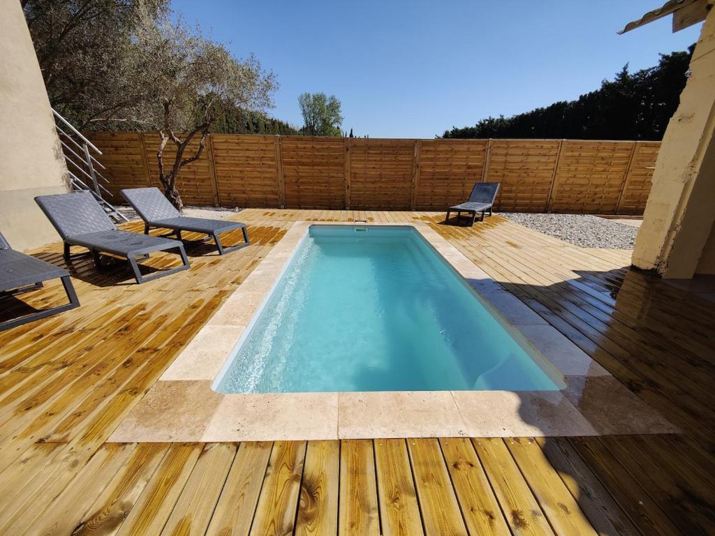 - une piscine sur une terrasse en bois avec 2 chaises dans l'établissement Superbe villa en Provence, piscine et pétanque, à Rognonas