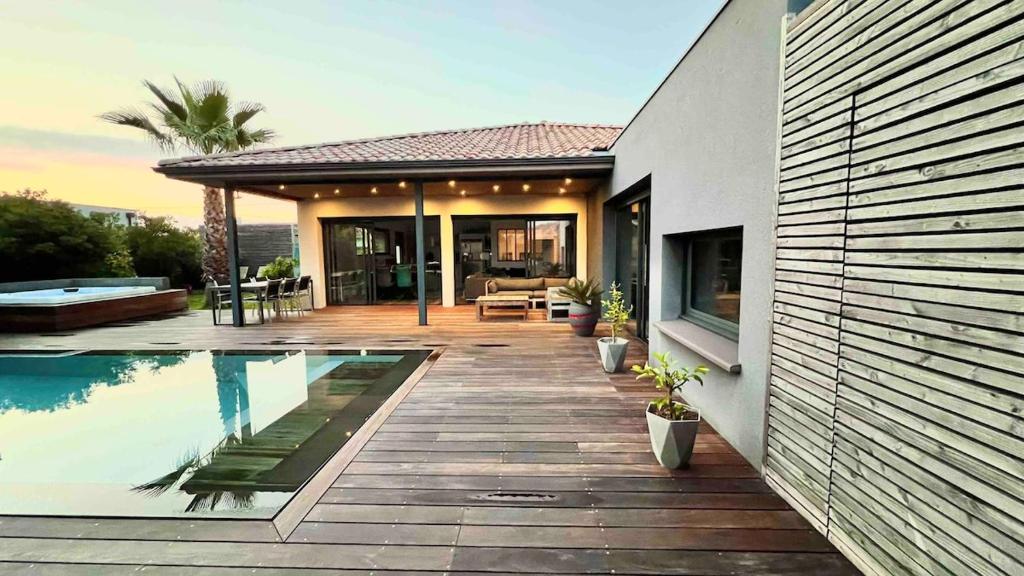 a house with a swimming pool next to a house at Villa Miroir d'O in Gujan-Mestras