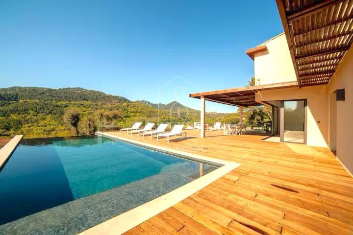 une maison avec une piscine et une terrasse en bois dans l'établissement Villa Corian, vue sur l'Estérel et piscine chauffée, à Les Adrets-de-l'Estérel