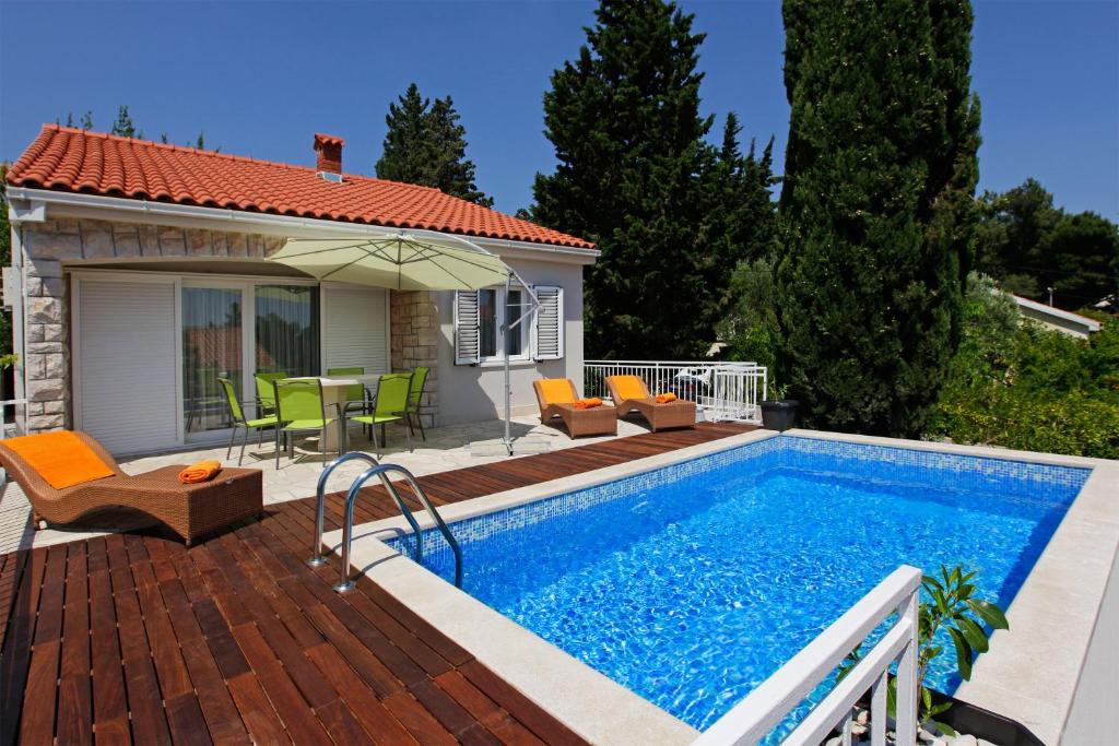 a swimming pool with a patio and a house at Vacation Home Villa Oleandra in Bol