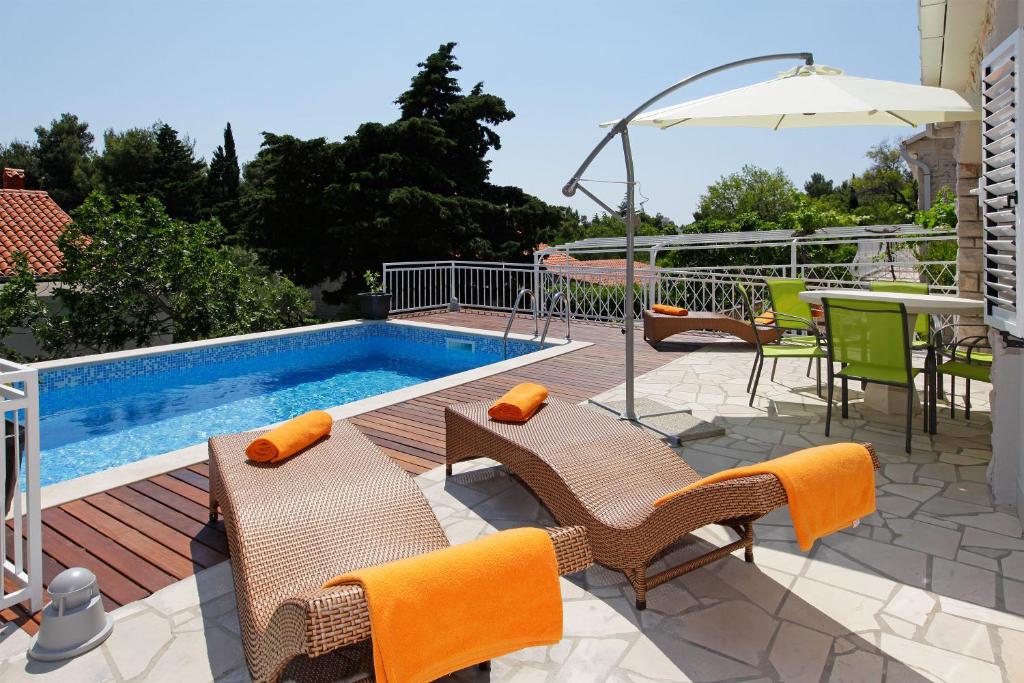 a patio with a pool and chairs and an umbrella at Vacation Home Villa Oleandra in Bol