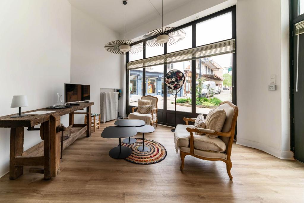 a living room with a desk and chairs and a table at Le Noyer - Maison design dans l'hyper centre in Vichy