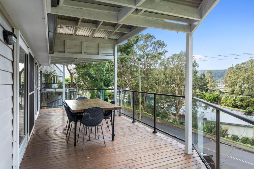 a porch with a wooden table and chairs on a balcony at The Hardys Bay Hideout in Hardys Bay