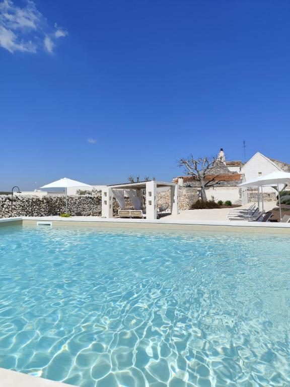 a swimming pool with blue water in front of a house at Borgo SantaMarta in Noci