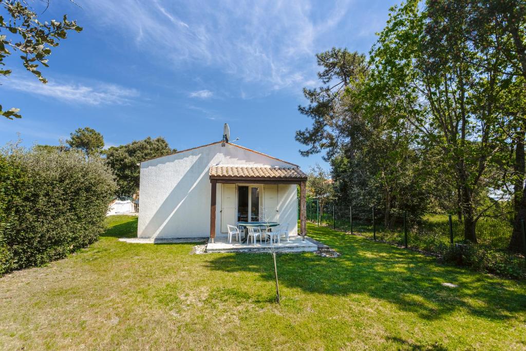 un petit bâtiment blanc avec une table dans une cour dans l'établissement Maison proche plage et centre ville, à Saint-Trojan-les-Bains