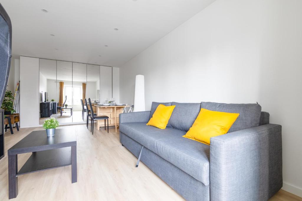 un salon avec un canapé gris et des coussins jaunes dans l'établissement 1 Bedroom Apartment Quartier Austerlitz Free Netflix, à Paris
