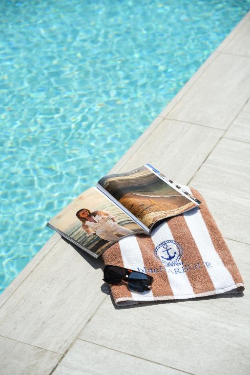 a book and a towel next to a swimming pool at Blue Harbour Boutique in Ayia Napa