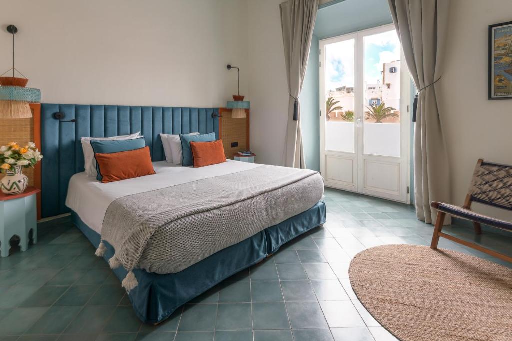 a bedroom with a large bed with orange and blue pillows at Le Palazzo in Essaouira