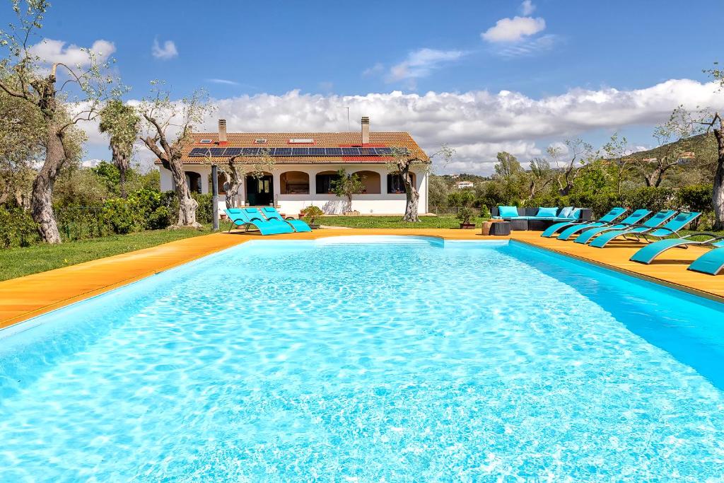 una piscina con sillas azules y una casa en ClickSardegna Villa Lucilla with swimming pool in olive groves, en Valverde