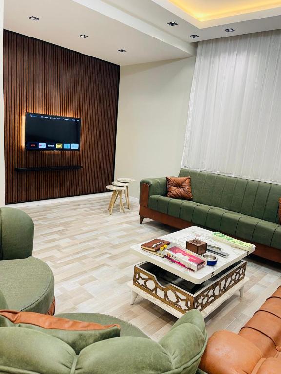 sala de estar con sofás verdes y TV en Amora Suites, en Estambul