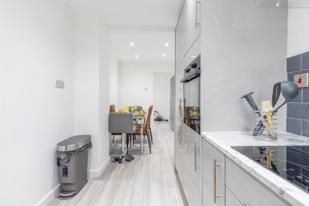 a white kitchen with a counter and a dining room at Newly Refurbed, Driveway, 4-BR House, Ensuite in Northampton