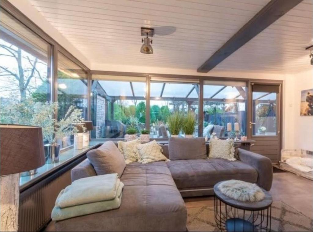 a living room with a couch and some windows at Lichtdurchflutetes Traumhaus 800 Meter zum Strandaufgang, uneinsehbarer Garten mit Terrassenüberdachung, hundefreundlich in Sint Maartenszee