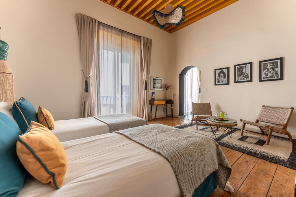 a bedroom with two beds and a table and chairs at Le Palazzo in Essaouira