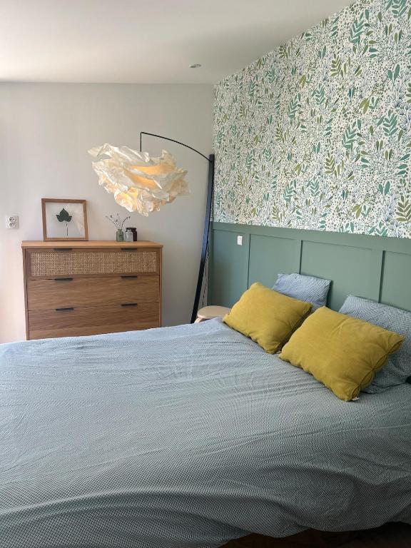 a bedroom with a bed with two yellow pillows at La Maison au fond du jardin - proche centre ville in Le Mans