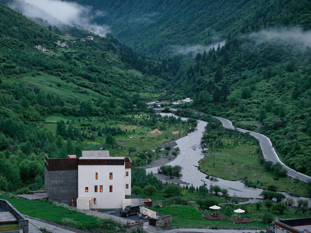 a building on a hill next to a river at DAINN Mt Siguniang in Mount Siguniang