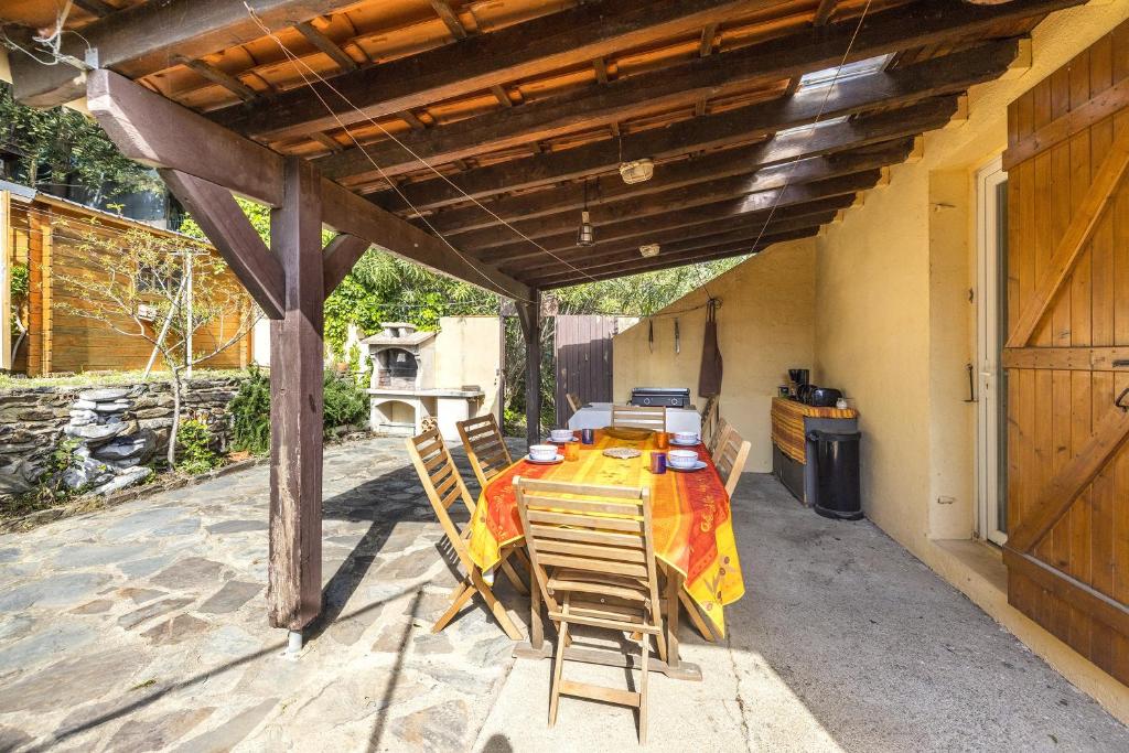 un patio avec une table et des chaises sous une pergola dans l'établissement La Belle Escapade - Climatisée aperçu mer, à Port-Vendres