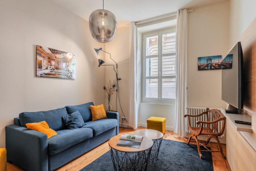 un salon avec un canapé bleu et une télévision dans l'établissement Le Clemenceau - Cœur historique de Nantes, à Nantes