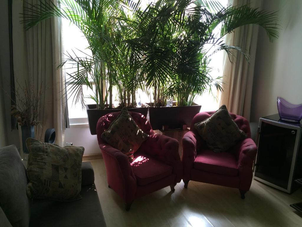 a living room with two chairs and plants in a window at Ipanema Dreams in Rio de Janeiro