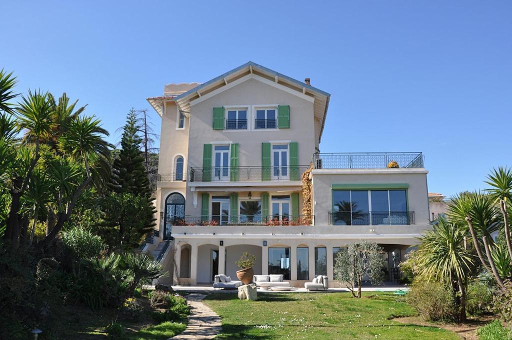 une grande maison avec des palmiers devant dans l'établissement Luxury Villa Pool & Sea View, à Nice