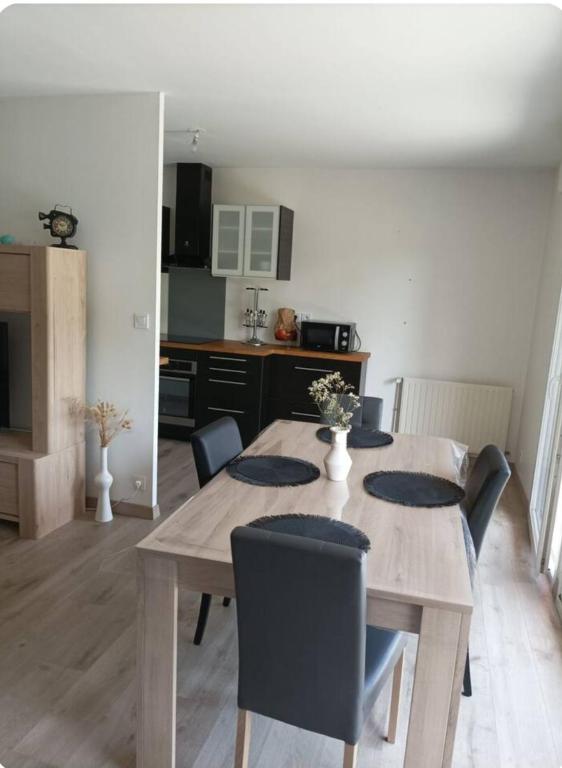 une salle à manger avec une table et des chaises en bois dans l'établissement Appartement quartier Beauregard à Rennes avec terrasse, à Rennes