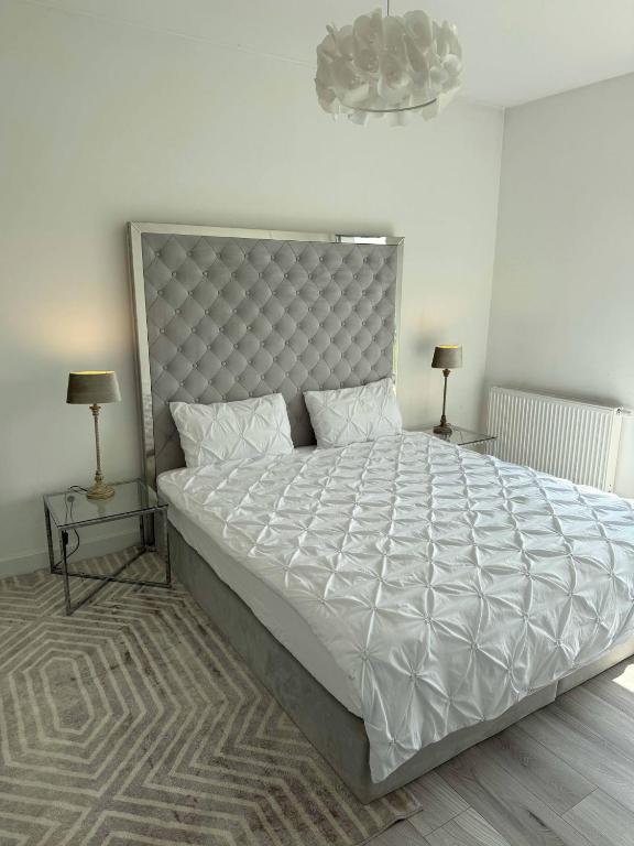 a bedroom with a large white bed with two lamps at Apartament 5 in Kobylniki