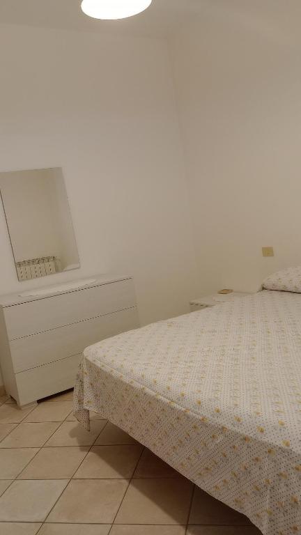 a white bedroom with a bed and a dresser at La casa di Franca in Formia