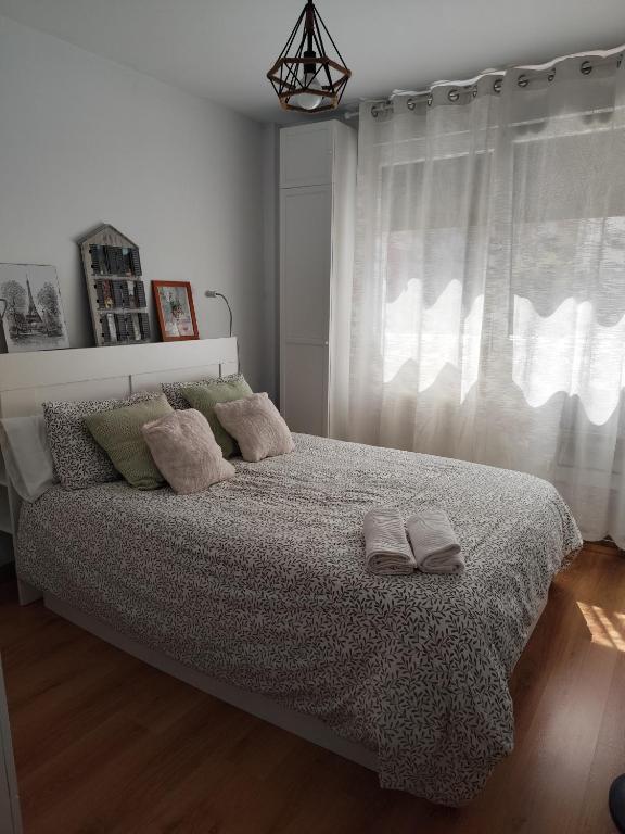 a bedroom with a bed with two pillows and a window at El apartamento de Fina in Gijón