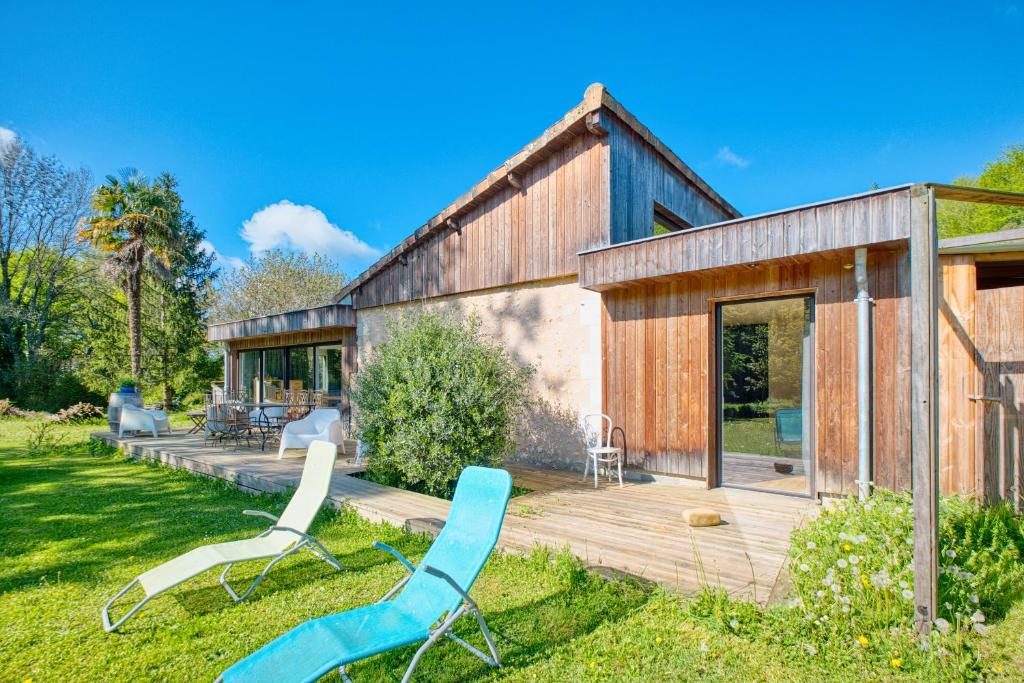 una casa con un ponte e due sedie nel cortile di La longère d'Astérius a Saint-Astier