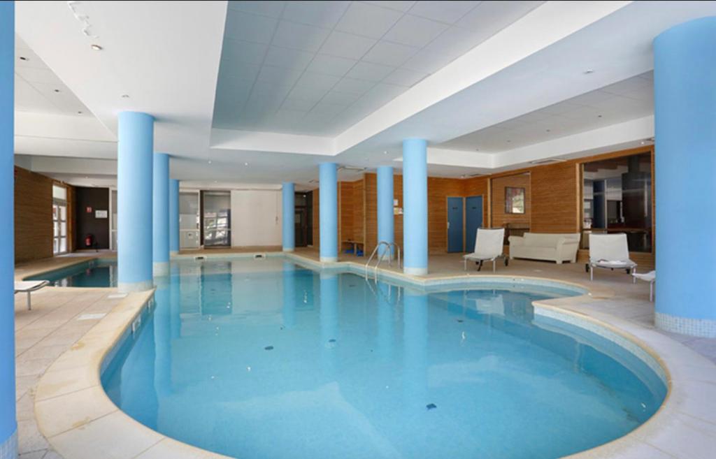 - une grande piscine avec colonnes bleues dans un bâtiment dans l'établissement Les chalets du verdon, à Allos