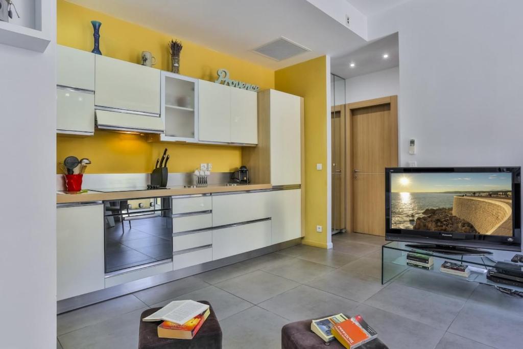 une cuisine avec des armoires blanches et une télévision à écran plat dans l'établissement FRANCE 82 D - 2 rooms - Terrace - 1 min to the Sea, à Nice