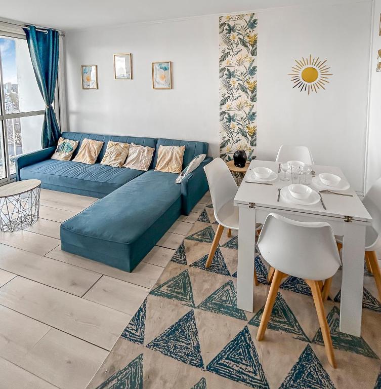 un salon avec un canapé bleu et une table dans l'établissement Lumineux avec balcon & confort familial, au Havre