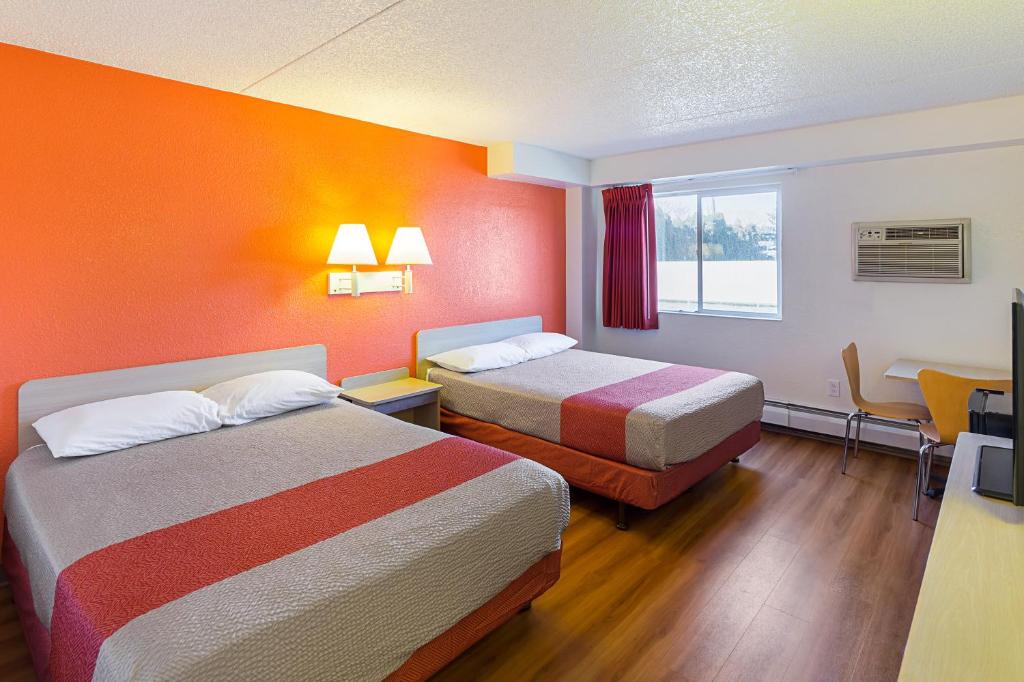 スポケーン・バレーにあるMotel 6-Spokane, WA - Eastのベッド2台とデスクが備わるホテルルームです。