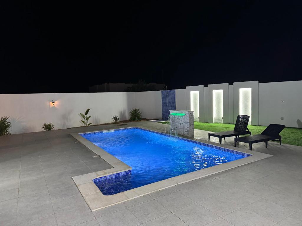 a swimming pool at night with two chairs next to it at Dar khadouja in Taguermess