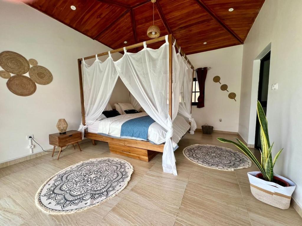 a bedroom with a canopy bed with rugs on the floor at Villa La Balinaise in Lomé