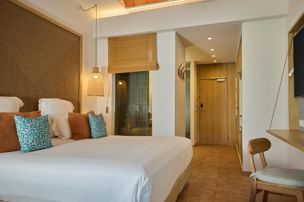 a bedroom with a large white bed in a room at Cala San Miguel Ibiza Resort, Adults only, Curio Collection by Hilton in Puerto de San Miguel