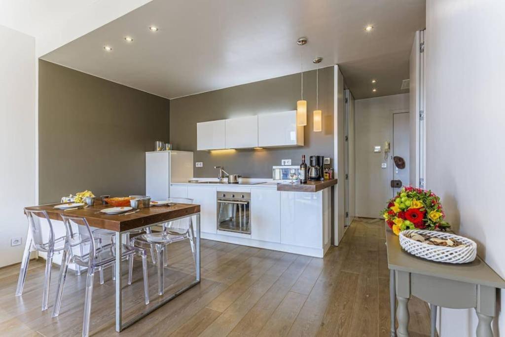 une cuisine avec des armoires blanches et une table et des chaises dans l'établissement FLEURS 22 - City Center - Modern w Terrace, à Nice