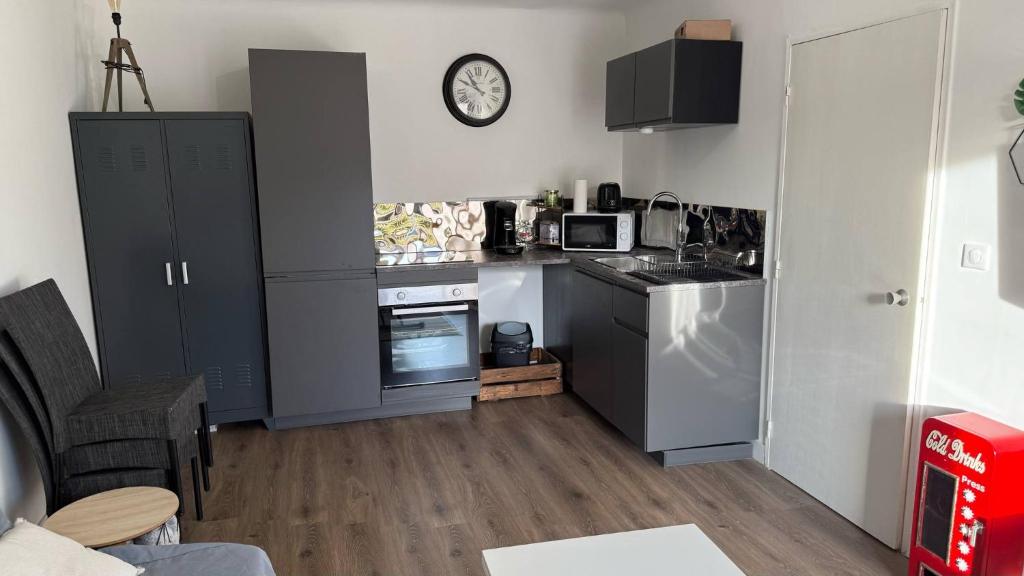 une cuisine avec des armoires grises et une horloge murale dans l'établissement Escapade de rêve à Saint-Raphaël, à Saint-Raphaël