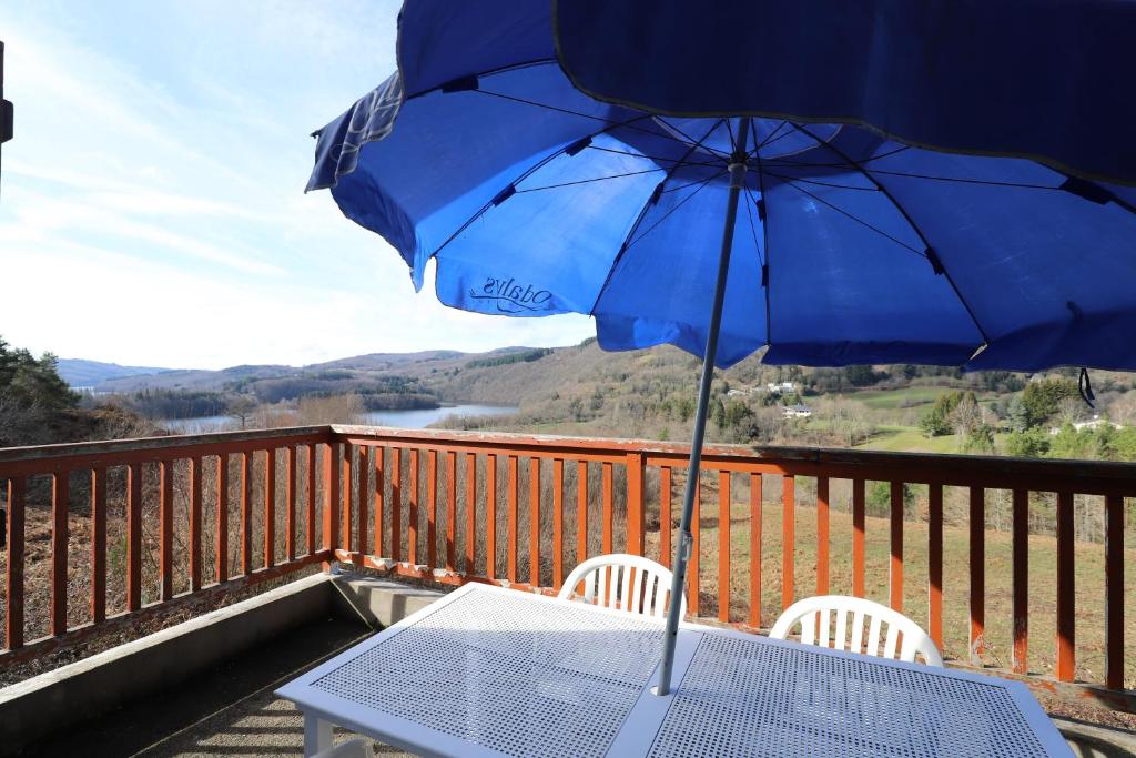- une table avec un parasol bleu sur le balcon dans l'établissement Gîte de Dom, à La Salvetat-sur-Agout