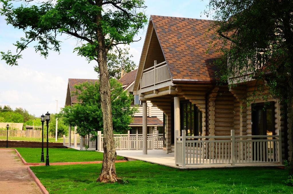 eine Blockhütte mit einer Veranda und einem Baum in der Unterkunft Pastoral Resort in Velikiy Les